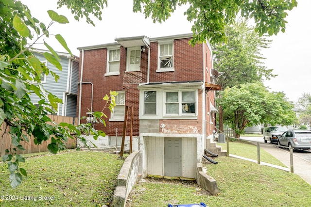 view of front of property featuring a front lawn, fence, and brick siding