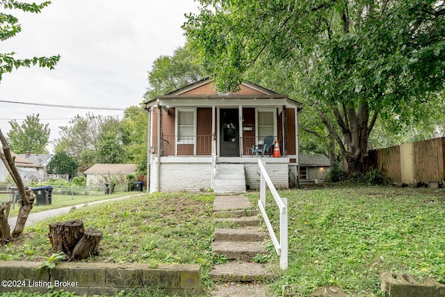 view of front of home featuring a porch, brick siding, fence, stairs, and a front lawn