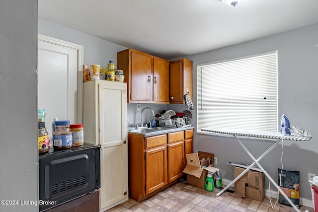 kitchen featuring black microwave, brown cabinets, a sink, and light countertops