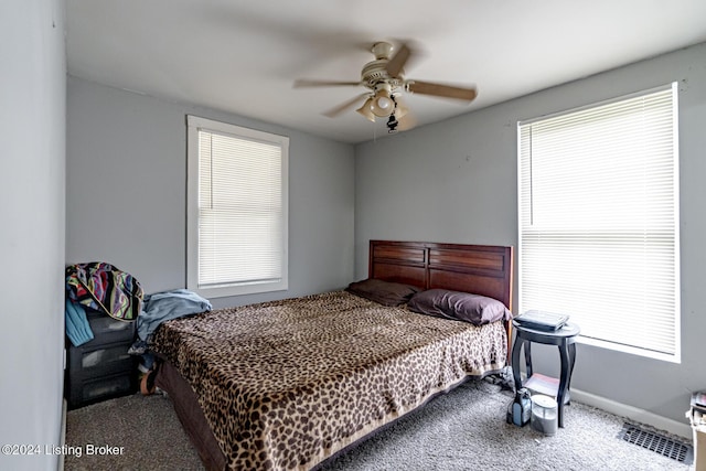 carpeted bedroom with baseboards, multiple windows, visible vents, and a ceiling fan