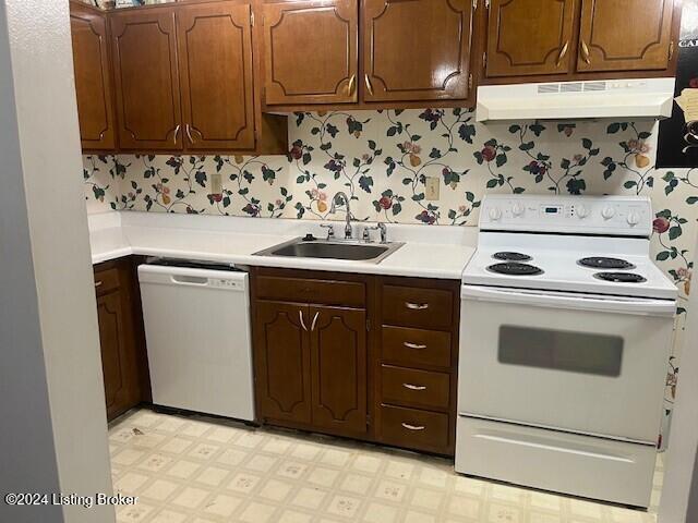 kitchen with under cabinet range hood, white appliances, a sink, light countertops, and light floors