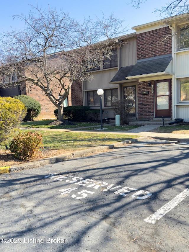 view of front of property featuring brick siding and roof with shingles