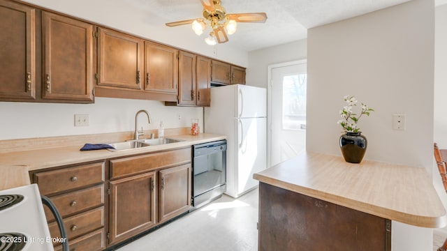 kitchen featuring a textured ceiling, white appliances, light countertops, and a sink