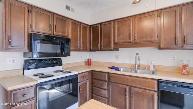 kitchen featuring black appliances, light countertops, and a sink