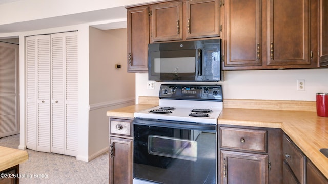 kitchen featuring baseboards, range with electric stovetop, black microwave, and light countertops