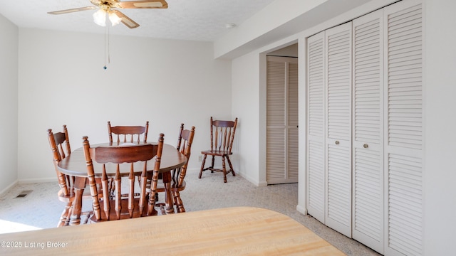 dining area featuring visible vents, a textured ceiling, baseboards, and a ceiling fan