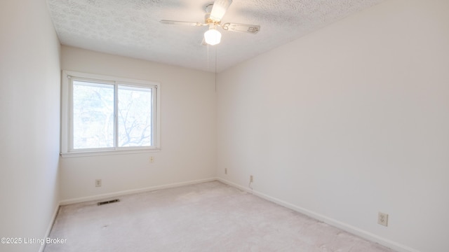 empty room featuring a ceiling fan, baseboards, visible vents, a textured ceiling, and light carpet