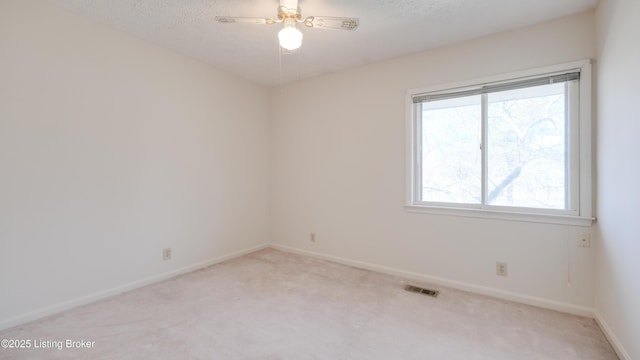 empty room with visible vents, baseboards, light carpet, a textured ceiling, and a ceiling fan