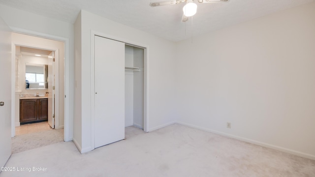 unfurnished bedroom with light carpet, baseboards, a closet, and a sink