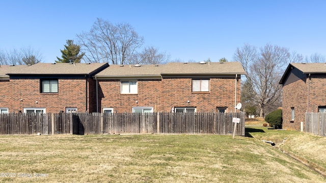 view of side of property with fence, a lawn, and brick siding