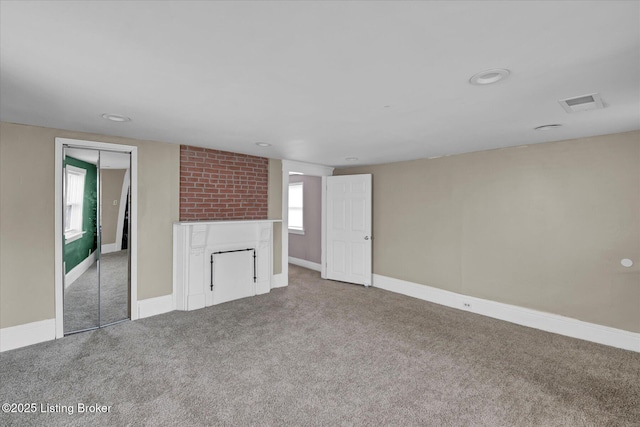 unfurnished living room with a large fireplace, baseboards, visible vents, and carpet flooring