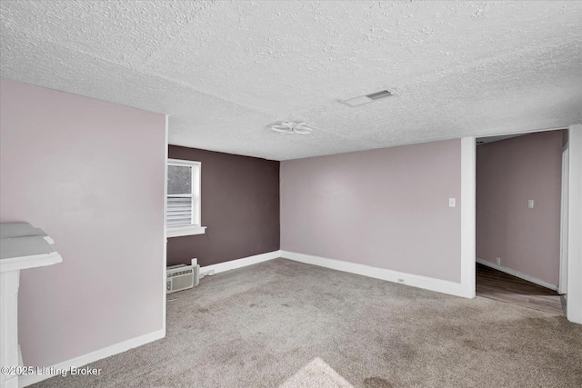 carpeted empty room featuring visible vents, baseboards, and a textured ceiling