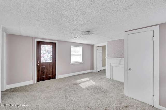 carpeted entrance foyer with a textured ceiling and baseboards