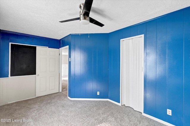 unfurnished bedroom with a textured ceiling, a closet, carpet, and a ceiling fan