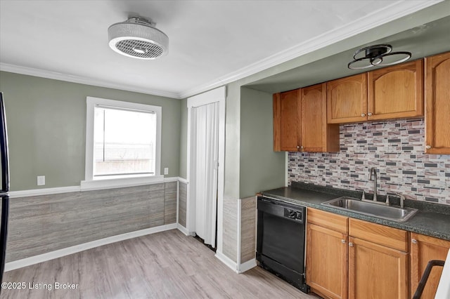 kitchen with black dishwasher, dark countertops, ornamental molding, light wood-style floors, and a sink