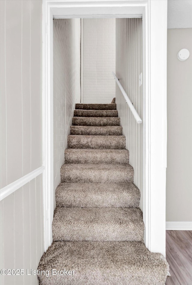 staircase featuring wood finished floors and baseboards