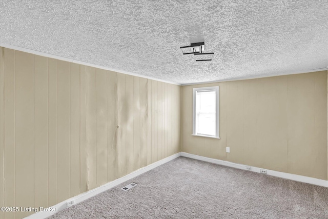 spare room with carpet floors, visible vents, and a textured ceiling