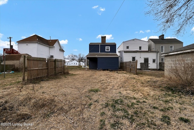 rear view of property featuring a storage unit, fence, and an outbuilding