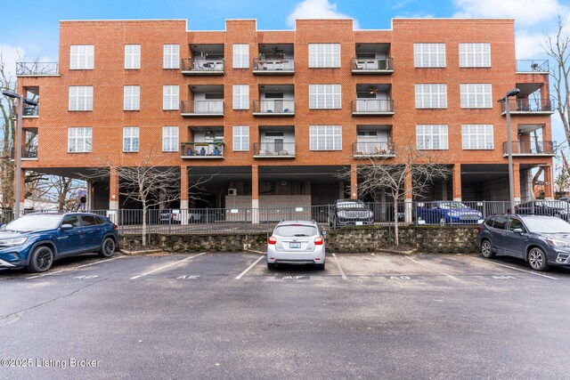 view of building exterior with uncovered parking and fence