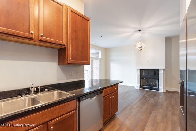 kitchen featuring a fireplace, stainless steel appliances, dark countertops, dark wood-type flooring, and a sink