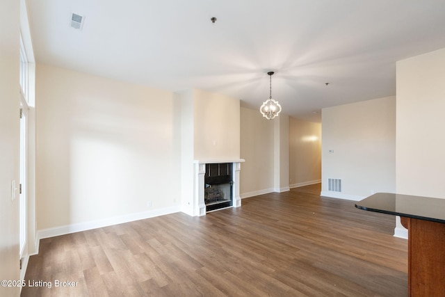 unfurnished living room featuring visible vents, a fireplace, baseboards, and wood finished floors