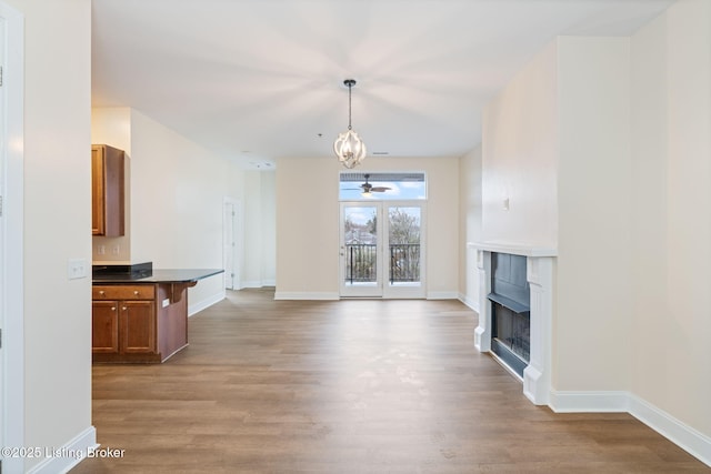 unfurnished living room with a fireplace, baseboards, and wood finished floors