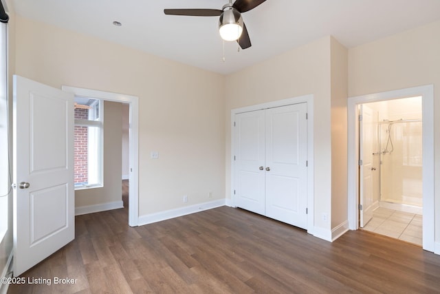 unfurnished bedroom featuring baseboards, connected bathroom, ceiling fan, wood finished floors, and a closet