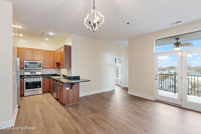 kitchen with visible vents, dark countertops, stainless steel appliances, light wood-type flooring, and a sink