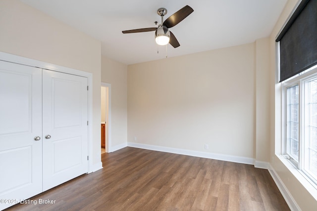 unfurnished bedroom with dark wood-type flooring, a closet, ceiling fan, and baseboards