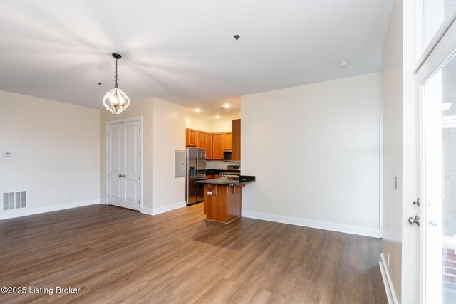 kitchen with stainless steel appliances, visible vents, open floor plan, dark countertops, and dark wood finished floors