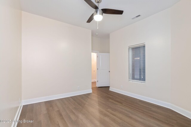 spare room with visible vents, wood finished floors, a ceiling fan, and baseboards