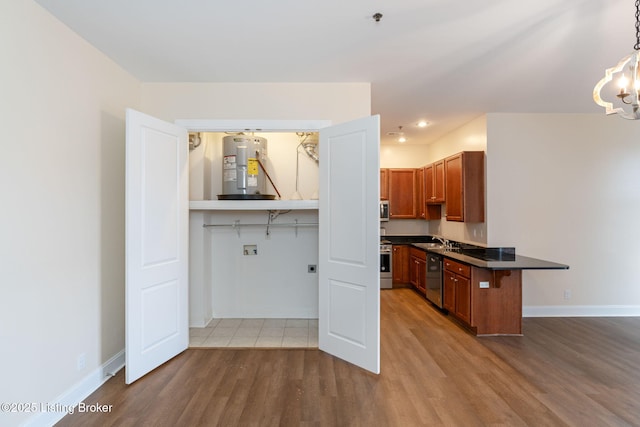 kitchen featuring stainless steel appliances, wood finished floors, water heater, brown cabinets, and dark countertops