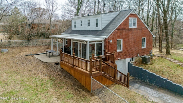 back of house featuring brick siding, central air condition unit, a sunroom, fence, and a garage