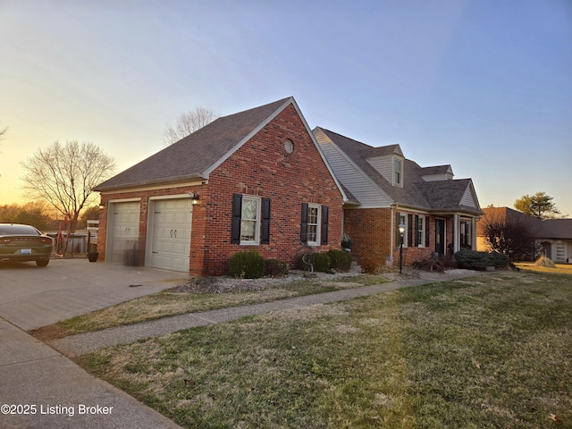 view of front of home with driveway, a lawn, roof with shingles, an attached garage, and brick siding