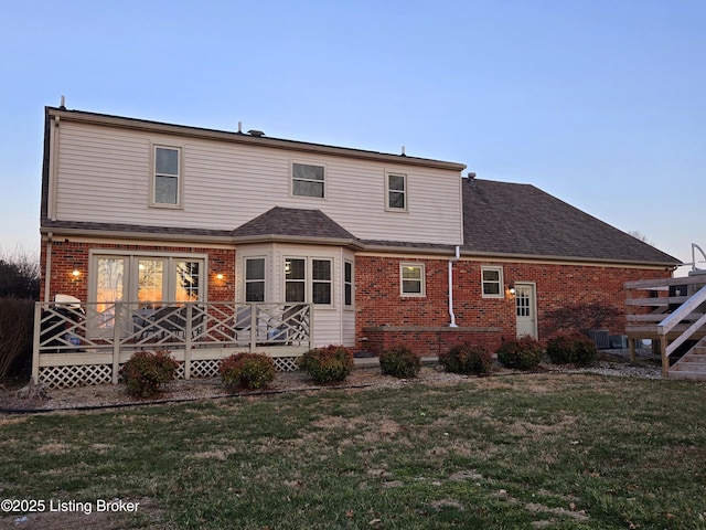 back of property with brick siding, a yard, a deck, and central air condition unit