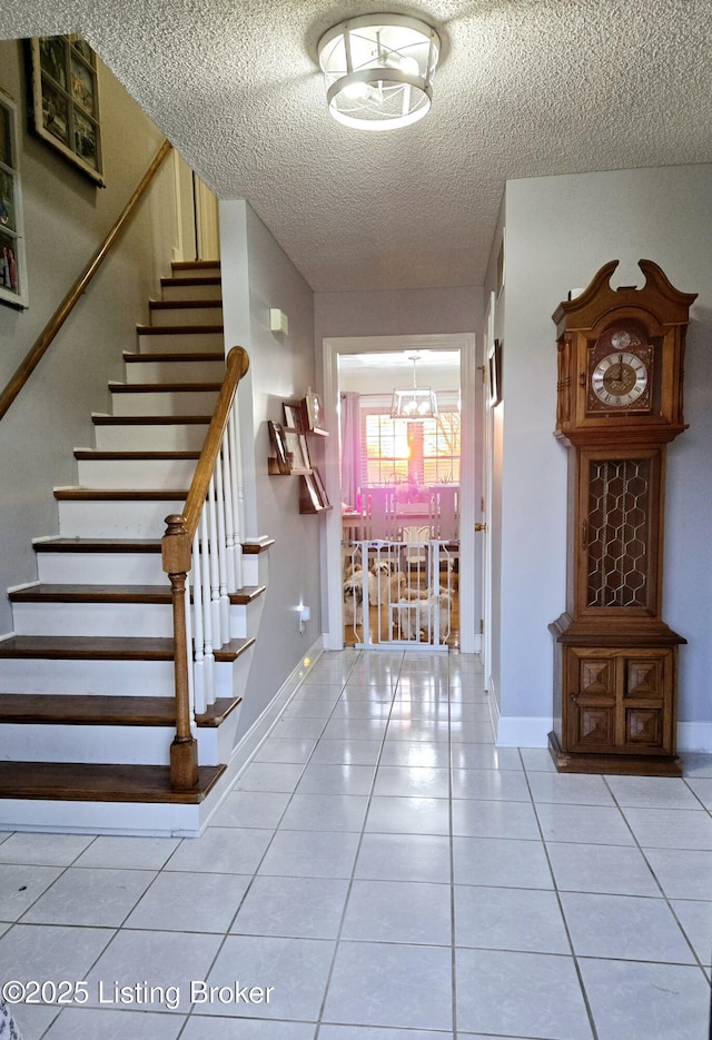 foyer entrance with baseboards, stairway, a textured ceiling, a notable chandelier, and light tile patterned flooring