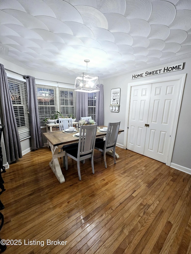 dining area with wood-type flooring, an inviting chandelier, and baseboards