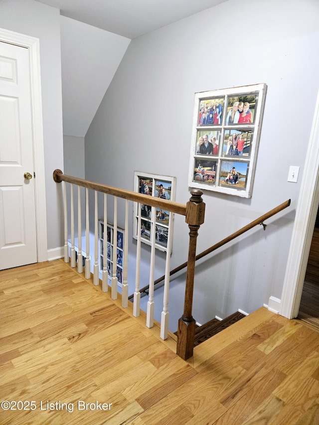 staircase with lofted ceiling, baseboards, and wood finished floors