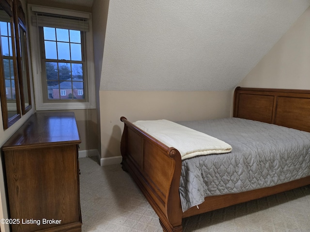 carpeted bedroom with vaulted ceiling, a textured ceiling, and baseboards