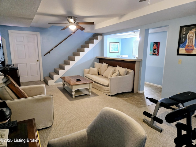 tiled living room with a ceiling fan, baseboards, and stairs