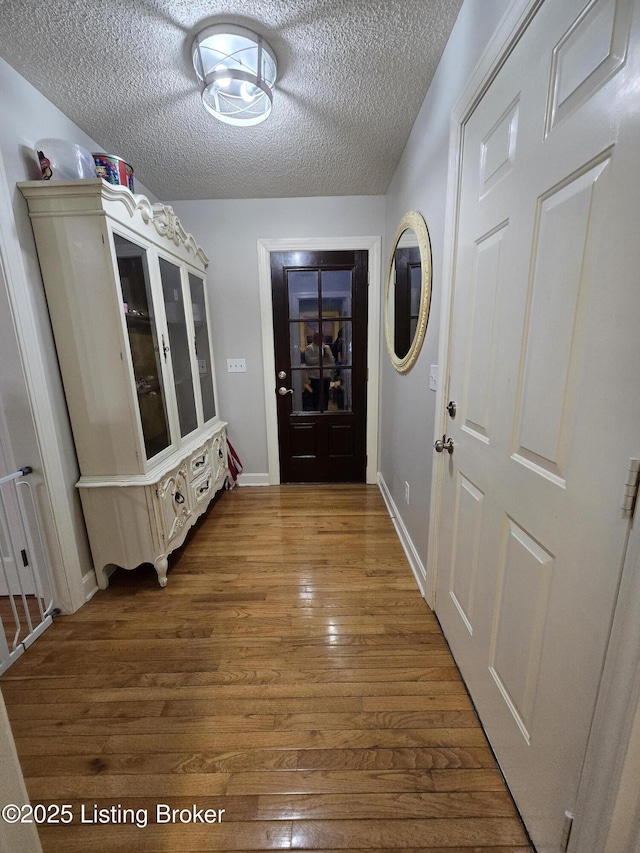 mudroom featuring dark wood finished floors, a textured ceiling, and baseboards