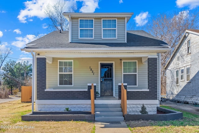 bungalow-style home featuring a porch, brick siding, and roof with shingles