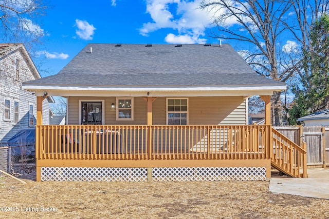 back of house with a porch and roof with shingles