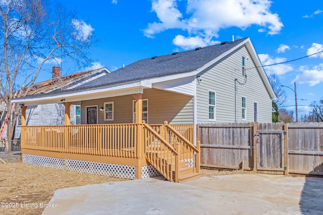 back of house with a shingled roof, fence, a porch, a patio area, and a gate