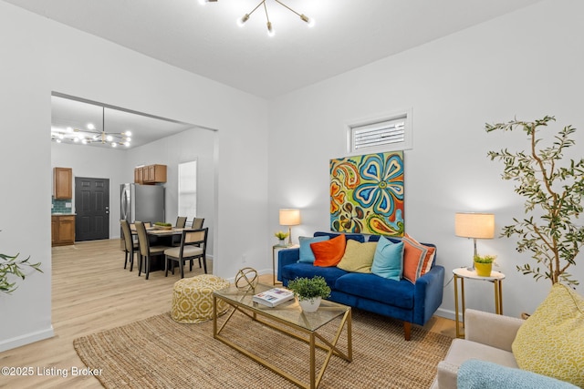 living room featuring an inviting chandelier, baseboards, and light wood finished floors