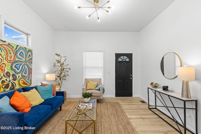 living area with baseboards, a notable chandelier, and wood finished floors