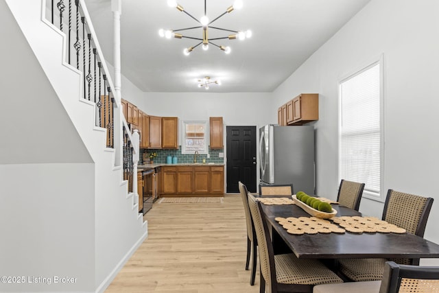 kitchen featuring electric stove, backsplash, freestanding refrigerator, brown cabinetry, and light wood finished floors