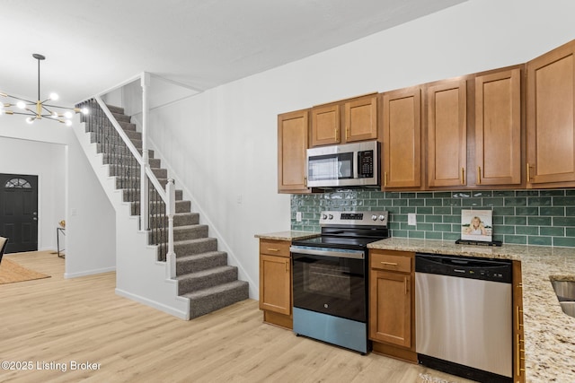 kitchen with brown cabinetry, backsplash, stainless steel appliances, and light wood-type flooring