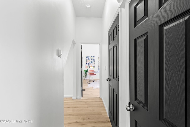 corridor with baseboards and light wood-type flooring