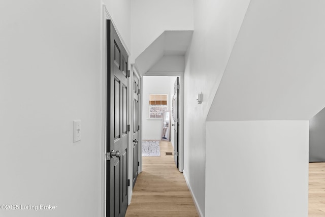 hallway featuring light wood finished floors and baseboards